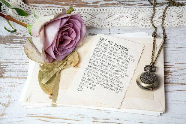 Purple rose and blank greeting card over wooden table. Top view with copy space